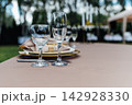Close-up of elegant wedding table setting with clear wine glasses and gold plate details. 142928330