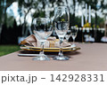 Close-up of elegant wedding table setting with clear wine glasses and gold plate details. 142928331