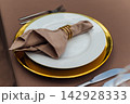 Elegant wedding table setting detail with plates, napkins and golden rings. 142928333