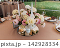 Elegant wedding table setting with floral centerpiece and candles under a marquee tent. 142928334