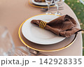 Elegant wedding table setting detail with plates, napkins and golden rings. 142928335
