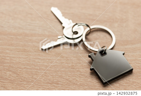 House keys with house shaped keychain on wood 142932875