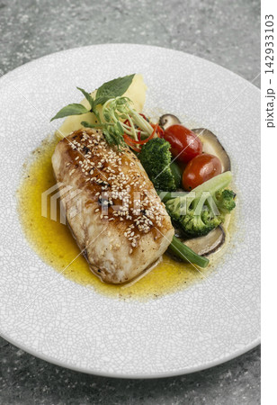 asian style fusion cod fillet with vegetables and sweet sesame ginger sauce on restaurant table 142933103