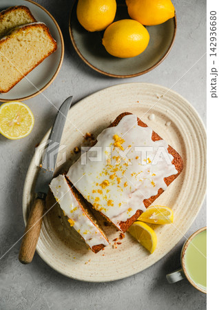 Lemon loaf cake slices with lemon glaze, fresh lemons and matcha tea, lifestyle food Lemon loaf cake slices with lemon glaze, fresh lemons and matcha tea, lifestyle food 142936680