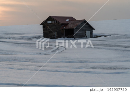 雪原に立つ木造の小屋と夕焼け 142937720