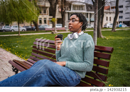 Young woman enjoying coffee and music in city park Young woman enjoying coffee and music in city park 142938215