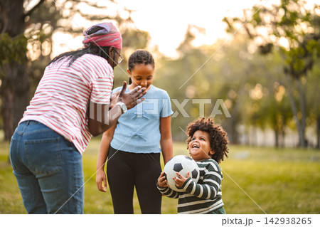 African American family playing with soccer ball in park African American family playing with soccer ball in park 142938265