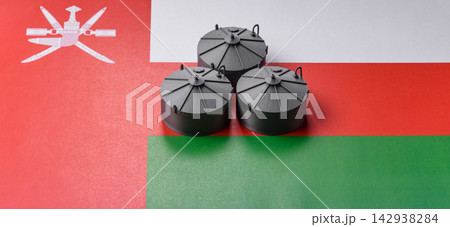 Liquefied gas storage tanks set against the Omani flag, representing the concept of supply 142938284