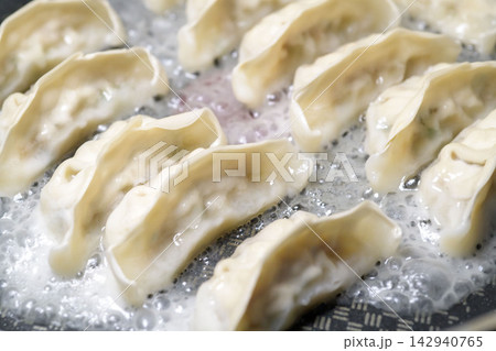沸騰したお湯の中で調理される餃子、もちもちの皮と具材が見える 沸騰したお湯の中で調理される餃子、もちもちの皮と具材が見える 142940765