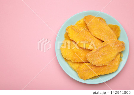 Slices of dried mango on mint plate on pink background. Space for text Slices of dried mango on mint plate on pink background. Space for text 142941806