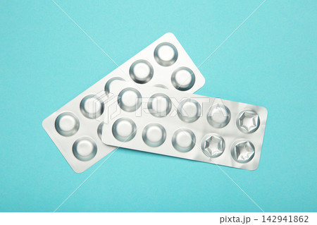 Silver metallic blister pack with tablets on blue background. 142941862
