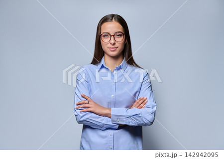 Young female student wearing eyeglasses and blue shirt on studio background 142942095