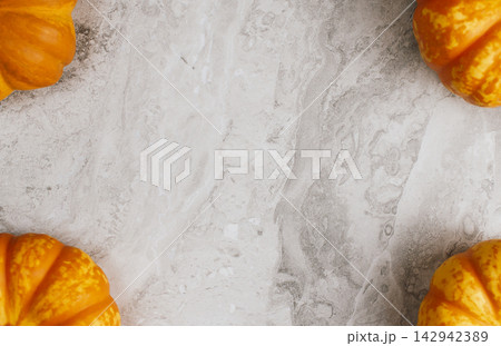 Fresh orange pumpkins set in four corners of light marble background creating central space for autumn promotional banner or seasonal festival announcement Fresh orange pumpkins set in four corners of light marble background creating central space for autumn promotional banner or seasonal festival announcement 142942389
