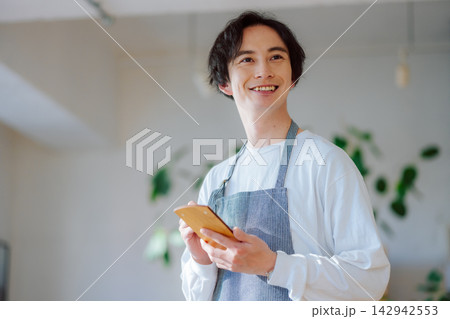 笑顔で接客するエプロン姿の男性店員 142942553