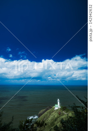 岬の突端に佇む白い灯台と連なる白雲の絶景 142942632