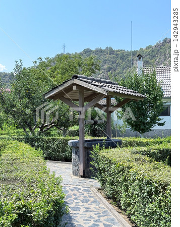 Traditional garden well surrounded by lush green landscaping Traditional garden well surrounded by lush green landscaping 142943285
