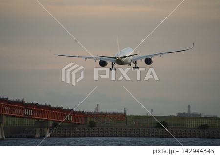 夕暮れの羽田空港へ着陸する旅客機 142944345