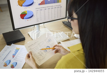 Woman analyst reviewing finance charts on computer, accounting data and forecast 142944855