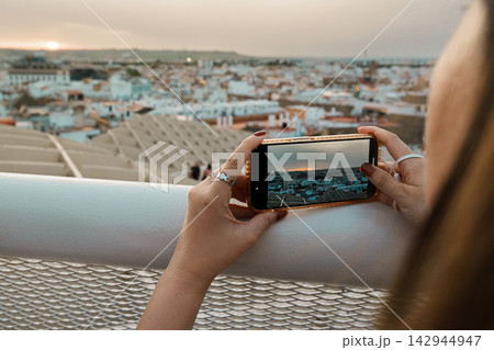 Close-up of hands photographing a sunset over Seville on a smartphone 142944947