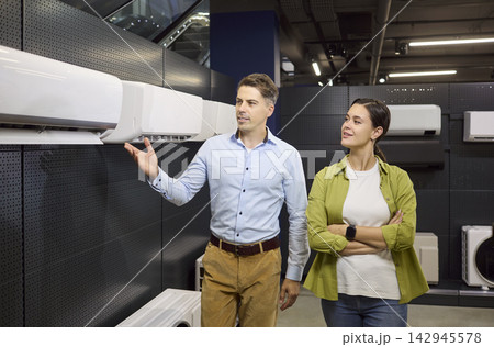 Smiling couple choosing air conditioner in retail appliance store interior Smiling couple choosing air conditioner in retail appliance store interior 142945578