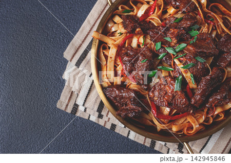 Udon noodles with beef in Mongolian style, with green onions and vegetables, homemade, on a dark background, 142945846