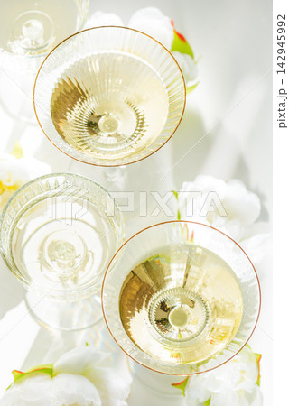 Four glasses filled with bubbly champagne and white flowers on a white background Four glasses filled with bubbly champagne and white flowers on a white background 142945992