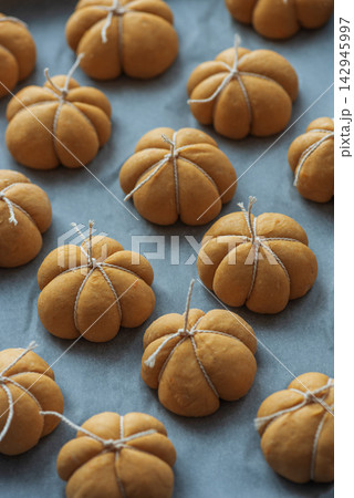Collection of small decorative pumpkin shaped baked goods tied with twine on baking paper Collection of small decorative pumpkin shaped baked goods tied with twine on baking paper 142945997
