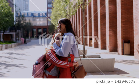 Mother and daughter enjoying a loving embrace outdoors, conveying belonging, emotional comfort and the reassuring closeness of their family bond 142946578