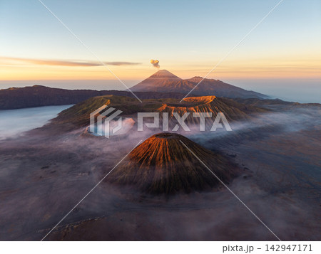 Majestic volcanoes rise above misty valleys at dawn 142947171