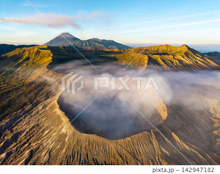 Majestic volcano rises above misty dawn glow 142947182