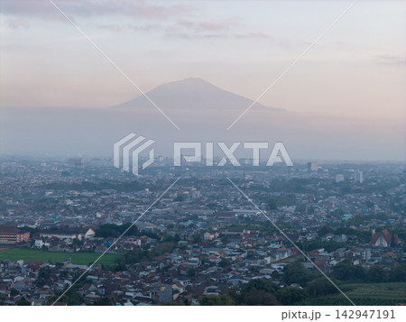 Misty mountain looms over sprawling cityscape 142947191
