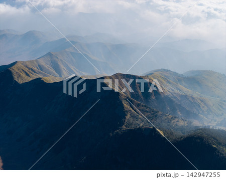 Layered mountain ridges stretch into misty distance Layered mountain ridges stretch into misty distance 142947255