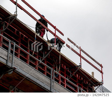 Construction Workers Handling Concrete Equipment on Upper Floor 142947525