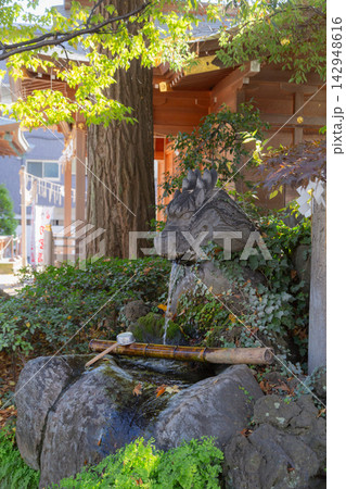 【日本】千葉県の松戸神社の手水舎に飾られた龍頭の石像から流れ出る水と柄杓 142948616
