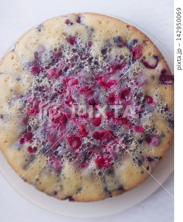 Round cake topped with red berries and bubbles on a white plate, overhead view Round cake topped with red berries and bubbles on a white plate, overhead view 142950069