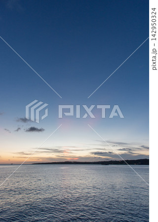 夕暮れに薄赤い薄明光線が見える穏やかな海 夕暮れに薄赤い薄明光線が見える穏やかな海 142950324