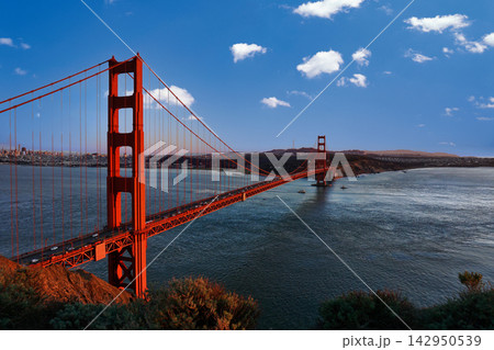 Golden Gate Bridge spanning the San Francisco Bay under a blue sky with clouds Golden Gate Bridge spanning the San Francisco Bay under a blue sky with clouds 142950539