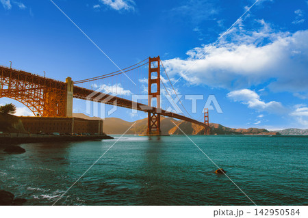 Golden Gate Bridge in San Francisco, California, spanning the bay under a blue sky with clouds. 142950584