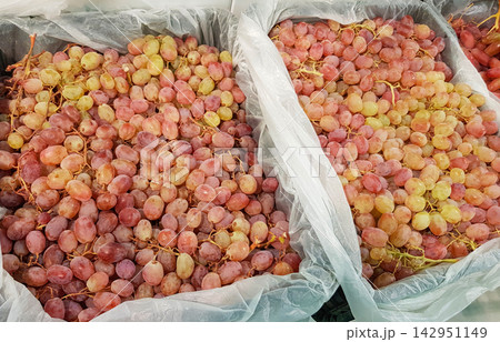 Lots of fresh ripe red grapes in containers on the market, close-up 142951149