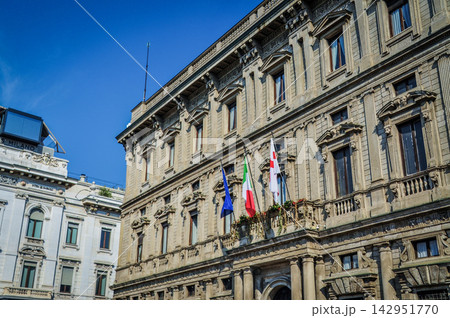 青空に映えるミラノの重厚な歴史的建造物とイタリア国旗 青空に映えるミラノの重厚な歴史的建造物とイタリア国旗 142951770