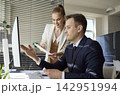 Team analysts discussing data dashboard on computer in bright modern office 142951994