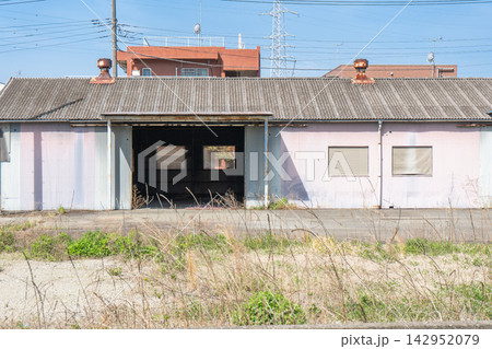 老朽化した平屋の倉庫・工場建物と草が生えた空き地2 142952079