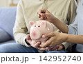 Hands placing coin in piggy bank, family savings for money management and wealth 142952740