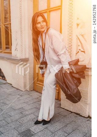 Woman city lifestyle leaning against stone building in warm morning sunlight holding leather jacket and bag Woman city lifestyle leaning against stone building in warm morning sunlight holding leather jacket and bag 142952768