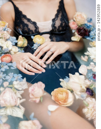 A woman in lace attire amidst vibrant flowers, with hands gently resting on their lap, creating an elegant and delicate aesthetic scene. concepts of beauty, serenity, and fashion 142952889