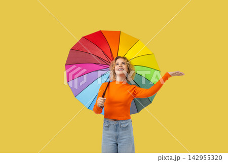 A girl smiles while holding a vibrant umbrella under clear skies A girl smiles while holding a vibrant umbrella under clear skies 142955320
