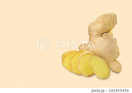 Fresh ginger root sits alongside sliced pieces on soft backdrop 142955450
