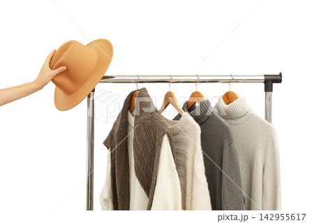 Fall clothing. Person selects a fashionable hat from a rack holding autumn outfits, PNG 142955617