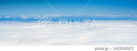 Panoramic view above a vast sea of white clouds under a clear blue sky with layered cloud formations stretching to the horizon 142958023