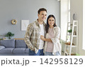 Portrait of young happy smiling couple standing in the living room at home together and hugging. 142958129